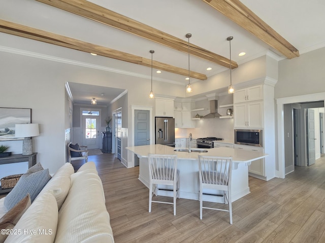 kitchen with a sink, open floor plan, wall chimney range hood, beamed ceiling, and high end appliances