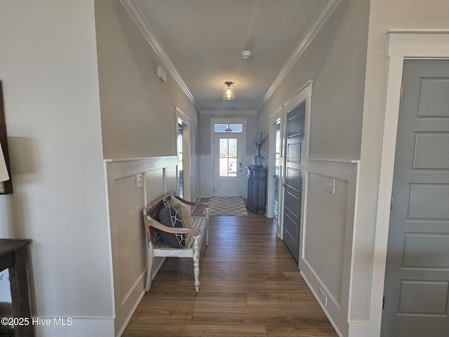 doorway to outside with dark wood finished floors, a wainscoted wall, crown molding, and a decorative wall