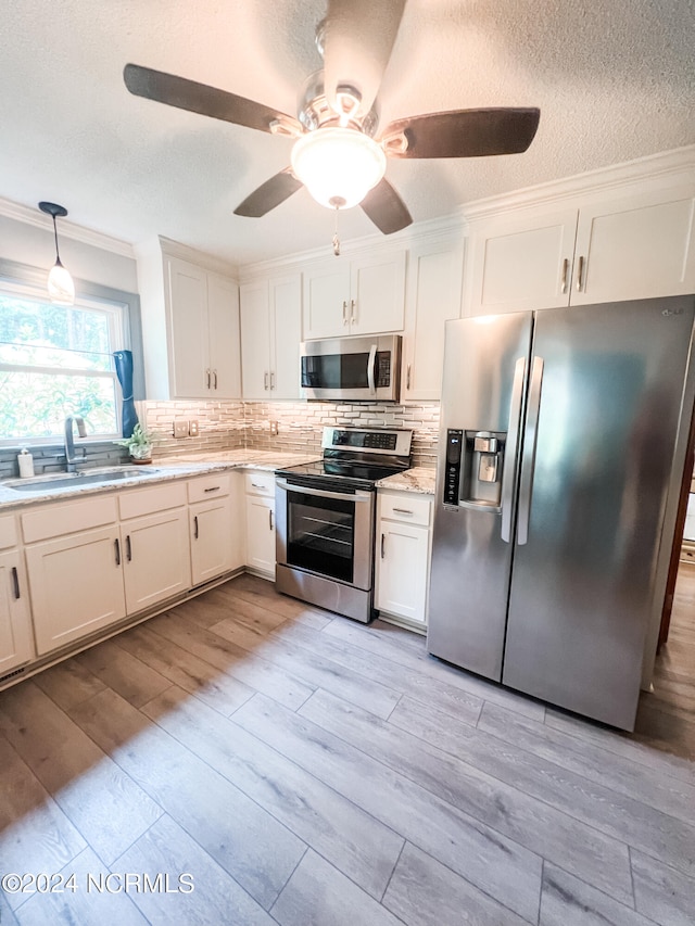 kitchen featuring pendant lighting, appliances with stainless steel finishes, sink, and white cabinetry