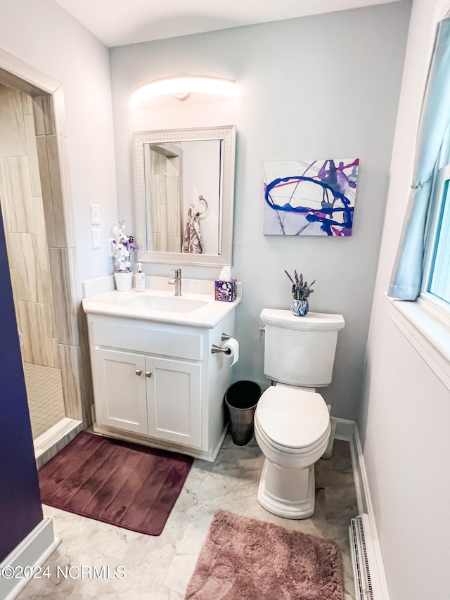 bathroom featuring toilet, tiled shower, vanity, and a baseboard heating unit