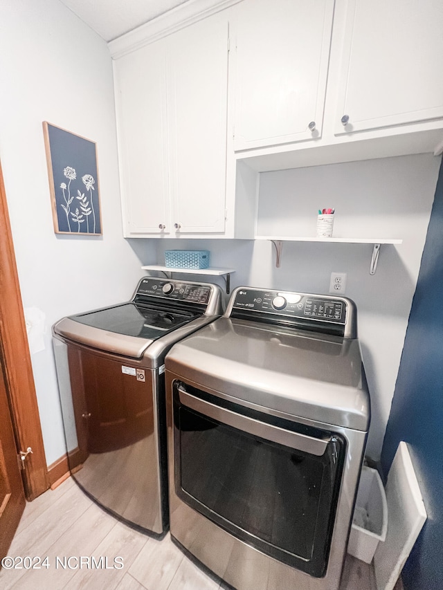 laundry room with light hardwood / wood-style floors, washer and dryer, and cabinets