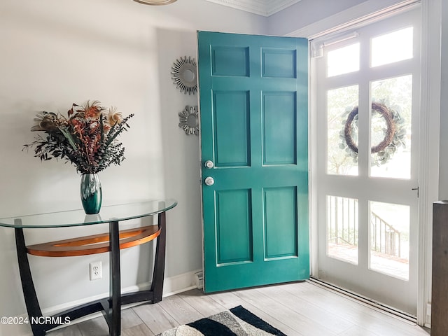 foyer featuring a healthy amount of sunlight, crown molding, and light hardwood / wood-style flooring