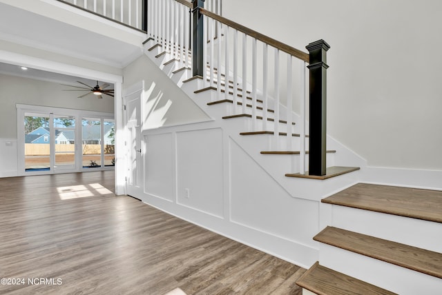 staircase with hardwood / wood-style floors and ceiling fan