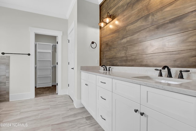 bathroom featuring a spacious closet, double vanity, crown molding, and a sink