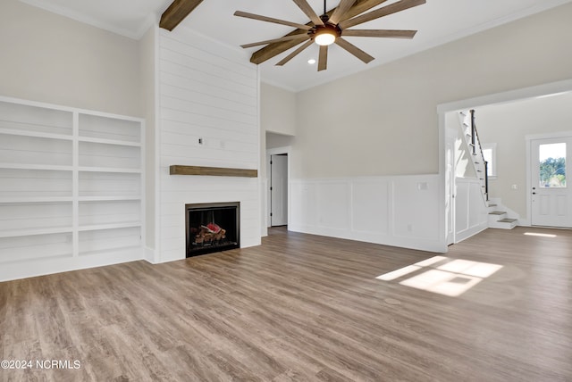 unfurnished living room featuring stairs, ornamental molding, a fireplace, wood finished floors, and a ceiling fan