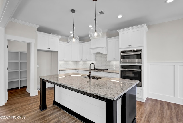 kitchen with white cabinetry, stainless steel appliances, dark wood-type flooring, and a center island with sink