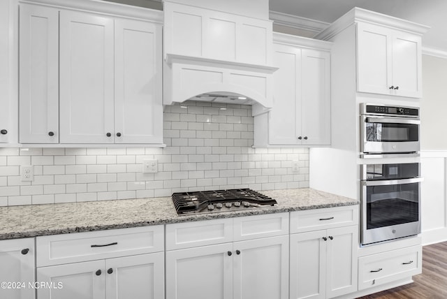 kitchen featuring appliances with stainless steel finishes, backsplash, white cabinetry, dark wood-type flooring, and ornamental molding