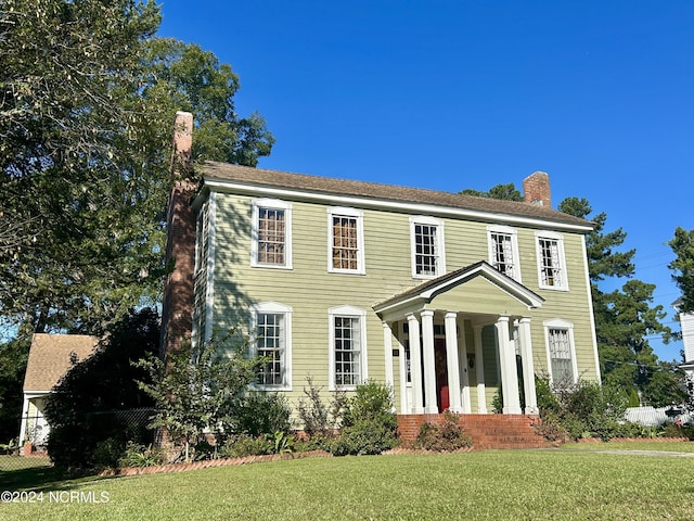 colonial inspired home featuring a chimney and a front lawn