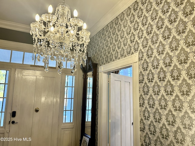 entrance foyer with a notable chandelier, ornamental molding, and wallpapered walls