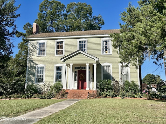 colonial house with a front yard and a chimney