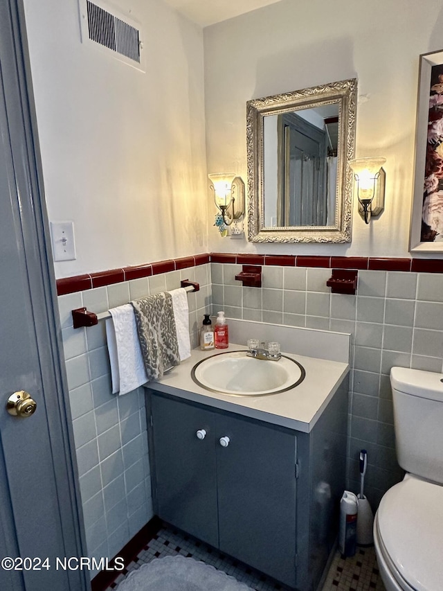 bathroom with visible vents, tile walls, toilet, and vanity