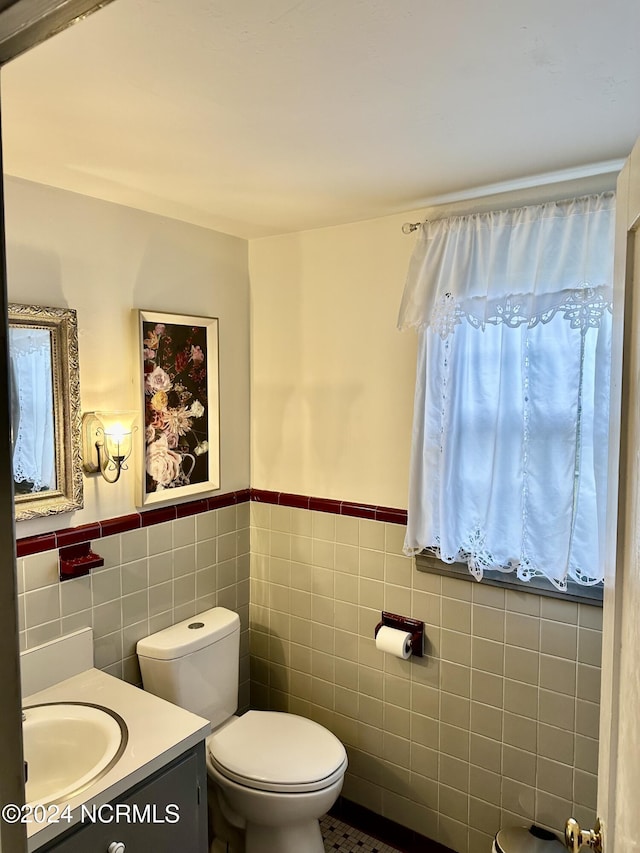 half bathroom featuring a wainscoted wall, toilet, tile walls, and vanity