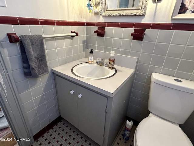 bathroom with tile walls, vanity, toilet, and tile patterned floors