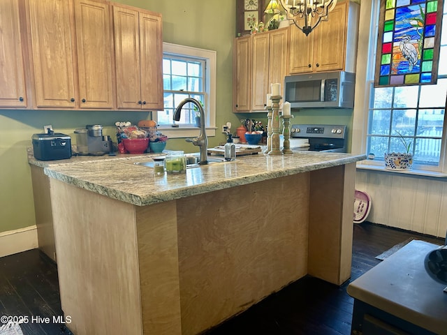 kitchen with baseboards, dark wood-style floors, appliances with stainless steel finishes, light stone countertops, and a sink