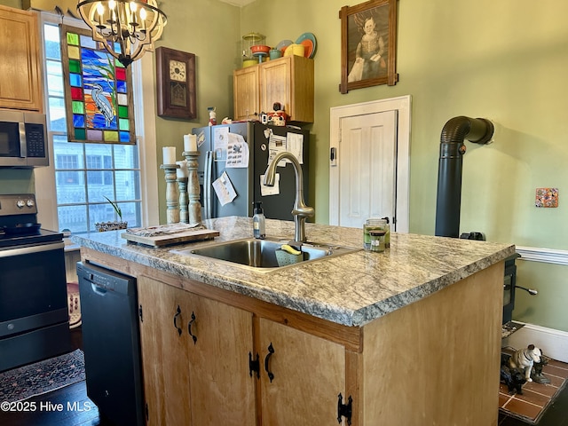 kitchen with appliances with stainless steel finishes, light countertops, a sink, and a center island with sink