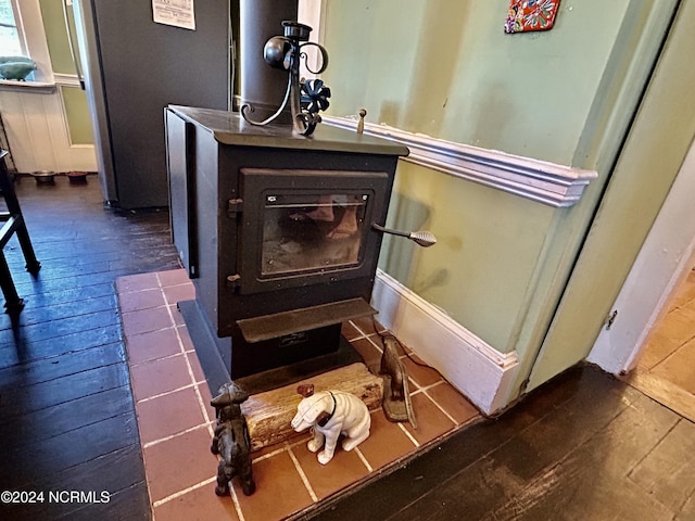 room details with wood finished floors, a wood stove, and baseboards