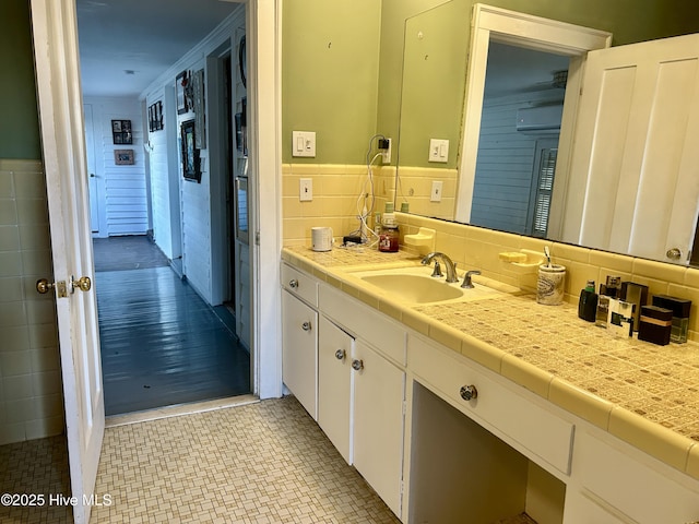 bathroom with wainscoting, vanity, and tile walls