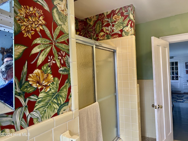 bathroom with a shower with door and wallpapered walls