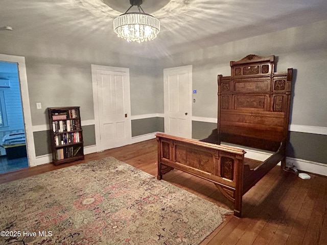 bedroom with dark wood-style floors, a chandelier, and baseboards