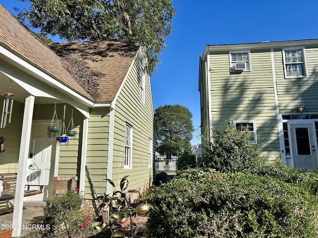 view of side of property featuring a shingled roof and cooling unit