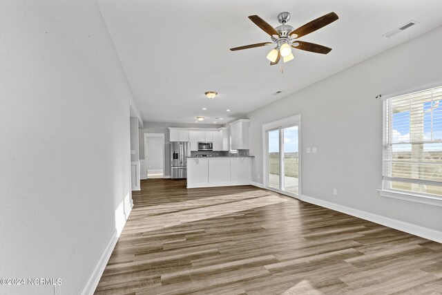 kitchen featuring sink, white cabinetry, stainless steel appliances, light stone countertops, and light hardwood / wood-style floors