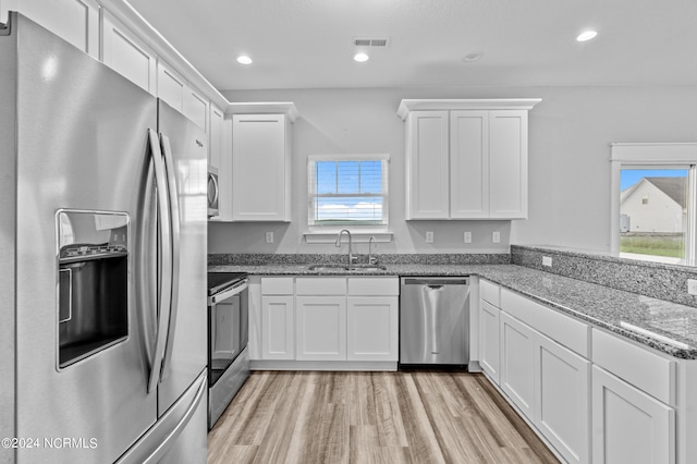 kitchen featuring white cabinetry, sink, stainless steel appliances, and dark stone countertops