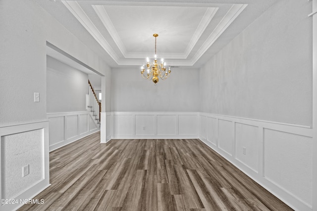 unfurnished room featuring crown molding, hardwood / wood-style flooring, a raised ceiling, and a chandelier