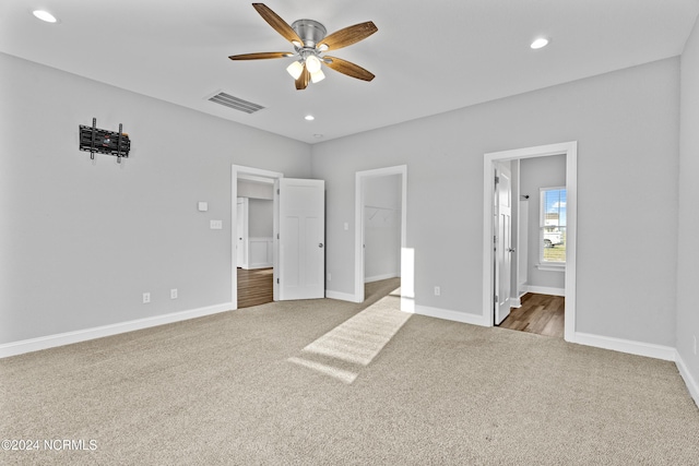 unfurnished bedroom featuring carpet, a spacious closet, ensuite bath, and a closet