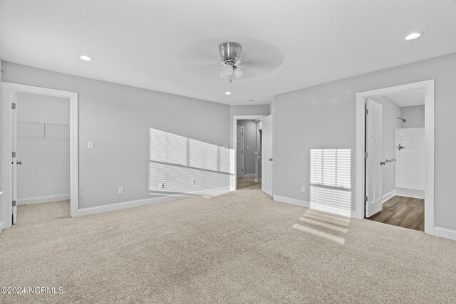 unfurnished bedroom featuring carpet floors, a walk in closet, ceiling fan, a closet, and ensuite bath