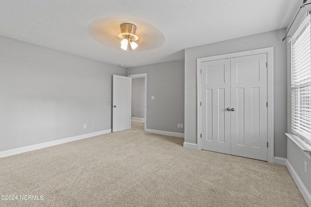 unfurnished bedroom with light colored carpet, a closet, and ceiling fan