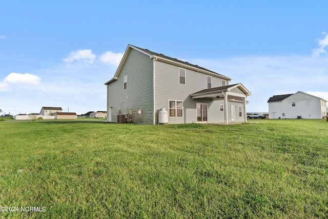 rear view of house with central AC and a yard