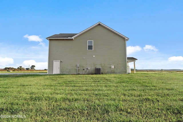 view of side of home with central AC and a lawn