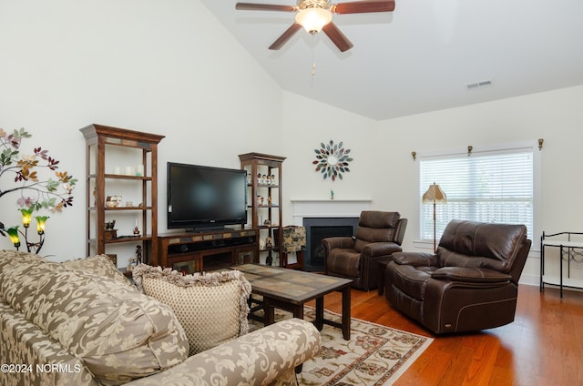 living room featuring wood finished floors, a fireplace, visible vents, a ceiling fan, and high vaulted ceiling