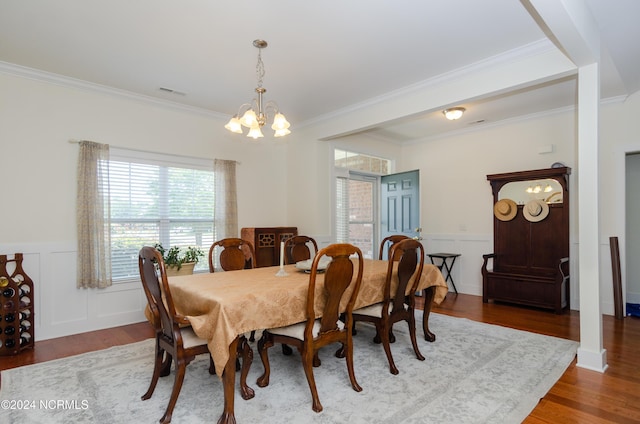 dining space featuring an inviting chandelier, crown molding, visible vents, wainscoting, and wood finished floors