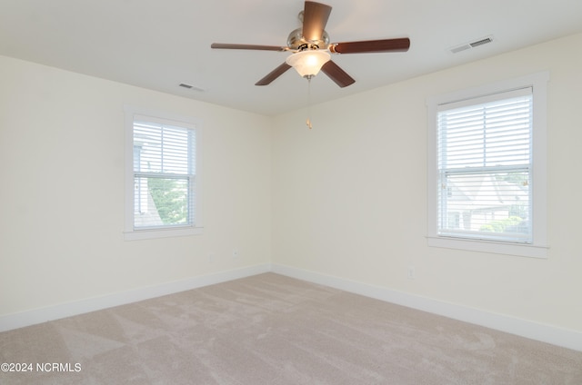 carpeted spare room featuring ceiling fan and a healthy amount of sunlight