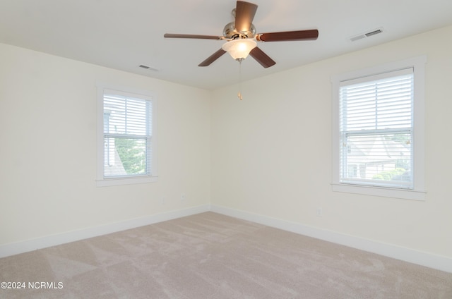 unfurnished room featuring visible vents, light colored carpet, and plenty of natural light