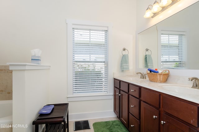 bathroom with a washtub, a wealth of natural light, tile patterned flooring, and vanity