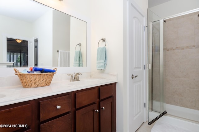 bathroom with a shower stall, double vanity, and a sink