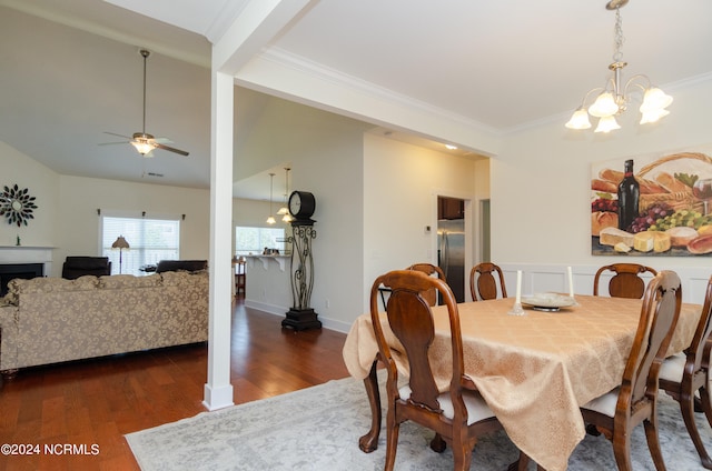 dining area with ornamental molding, dark wood-type flooring, and ceiling fan with notable chandelier