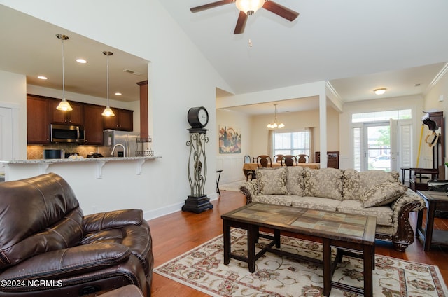 living room with lofted ceiling, visible vents, baseboards, dark wood-type flooring, and ceiling fan with notable chandelier