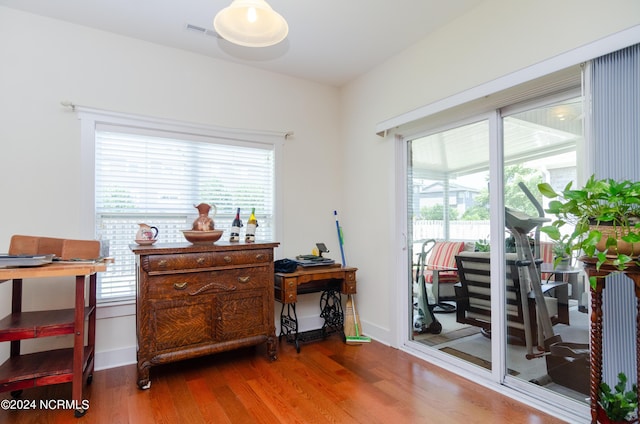 interior space featuring baseboards, visible vents, wood finished floors, and plenty of natural light
