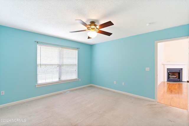 carpeted empty room featuring a textured ceiling and ceiling fan