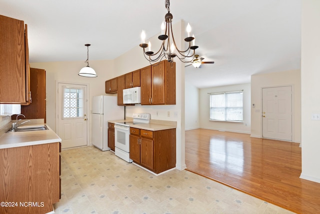 kitchen with white appliances, sink, light hardwood / wood-style floors, vaulted ceiling, and decorative light fixtures