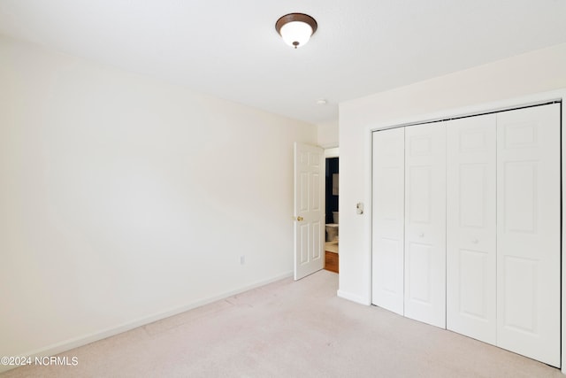 unfurnished bedroom with a closet and light colored carpet