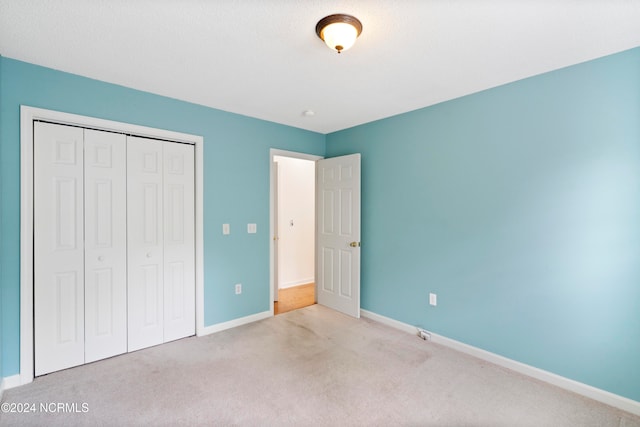 unfurnished bedroom with light carpet and a closet