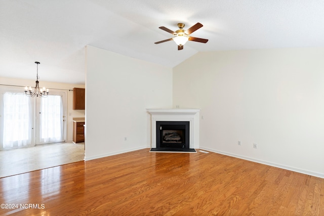 unfurnished living room featuring vaulted ceiling, light hardwood / wood-style flooring, and ceiling fan with notable chandelier