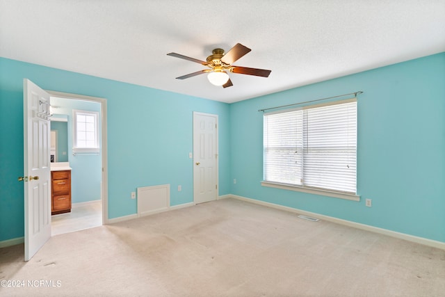 unfurnished bedroom with a textured ceiling, light colored carpet, and ceiling fan