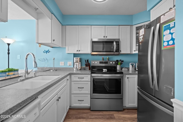 503 Pelican Ct Unit 503, Kure Beach, NC 28449 - kitchen with dark wood finished floors, appliances with stainless steel finishes, white cabinetry, and a sink
