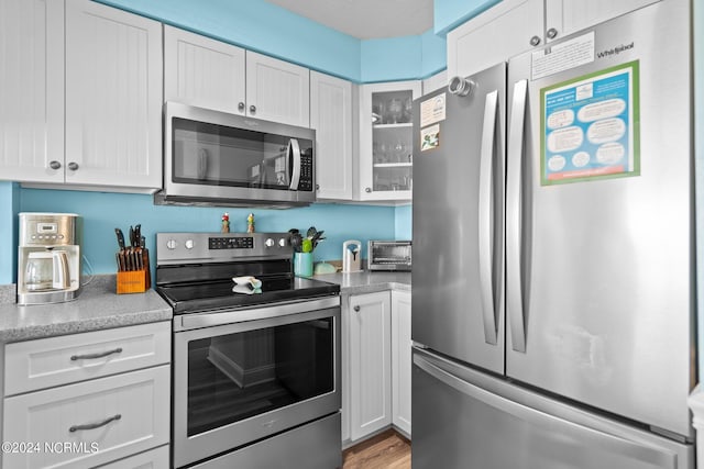 503 Pelican Ct Unit 503, Kure Beach, NC 28449 - kitchen featuring light countertops, glass insert cabinets, light wood finished floors, white cabinetry, and appliances with stainless steel finishes