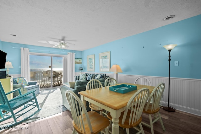 dining area featuring ceiling fan, hardwood / wood-style flooring, and a textured ceiling